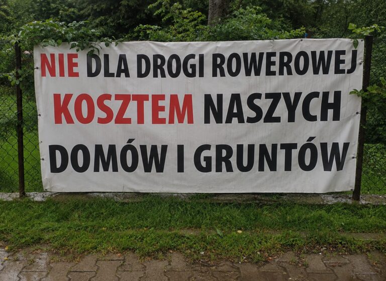 Banery „Nie dla drogi rowerowej” w gminie Jeleśnia. W tle domy, działki i przebudowa DW945